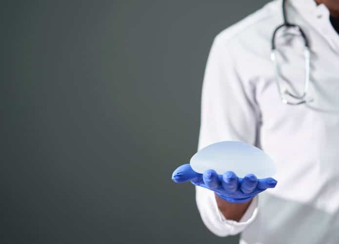 Médico segurando implante mamário