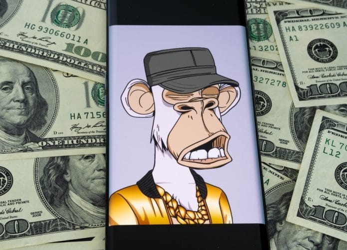 NFT da coleção Bored Ape Yacht Club vista na tela de um smartphone com notas de dólares ao fundo