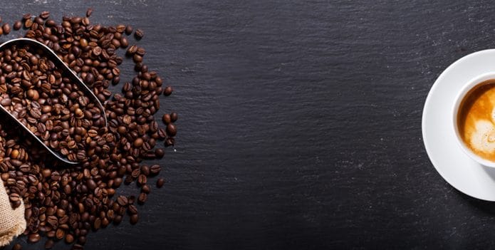 Grãos de café ao lado de uma xícara da bebida