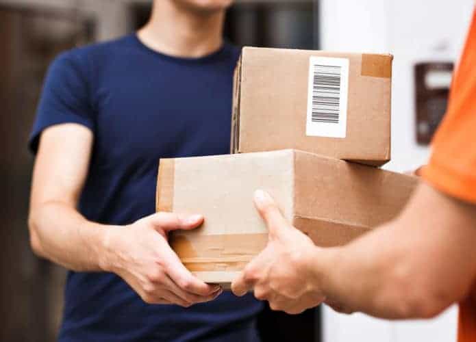 Pessoa vestindo uma camiseta laranja entrega encomendas a um cliente; serviço de entrega; logística; prazo de entrega.