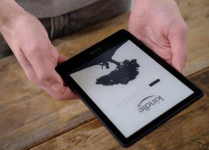 Mãos segurando um Kindle, o leitor de e-books da Amazon.