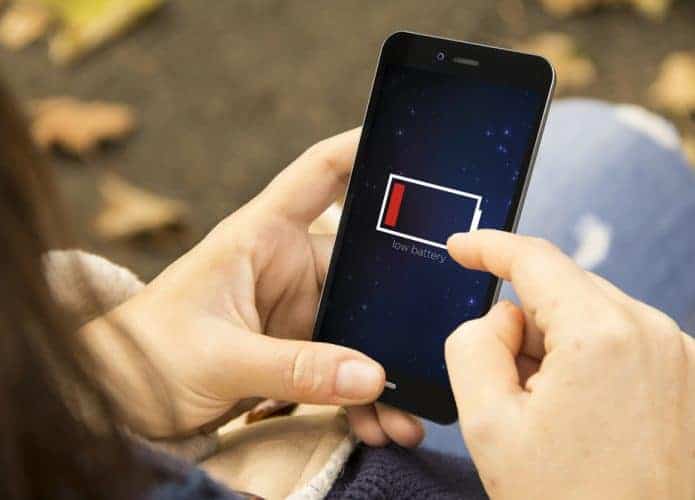 Mulher segurando um celular com pouca carga de bateria.
