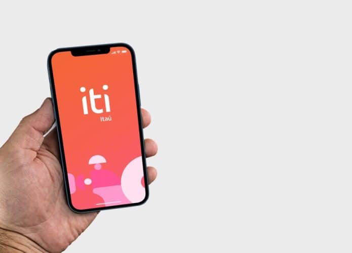 Mão masculina segurando celular com logotipo do Iti Itaú