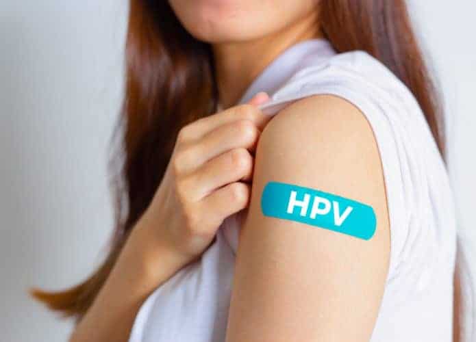 Mulher com o braço mostrando um adesivo onde recebeu vacina contra o HPV
