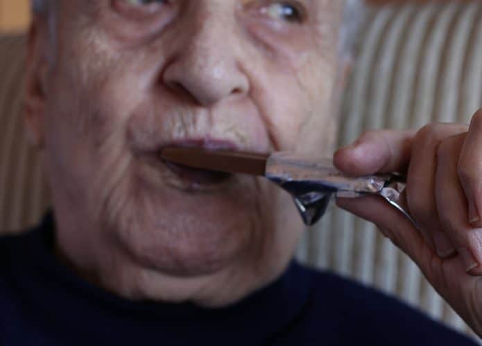Um idoso comendo chocolate