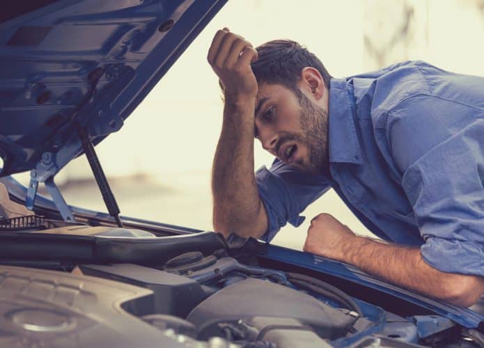 Jovem tendo problemas com o seu carro; carro quebrado