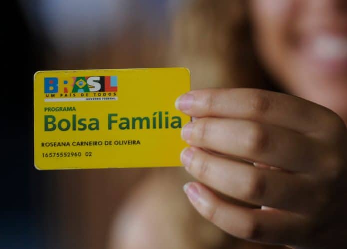 Mulher segurando cartão do Bolsa Família