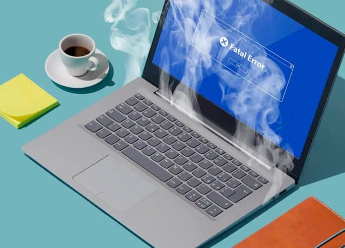 Notebook superaquecendo ao lado de café, bloco de post-its e caderno de anotações