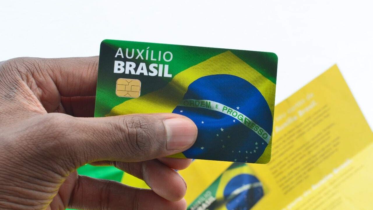 Homem segurando cartão do Auxílio Brasil