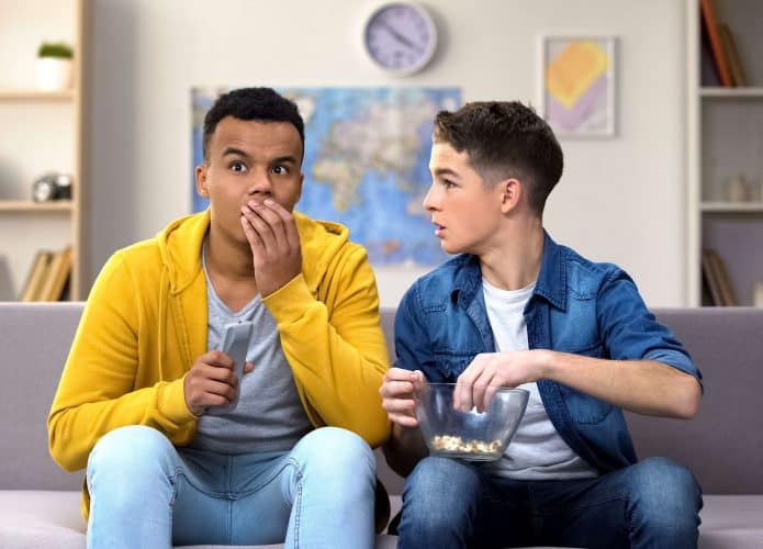 Adolescentes em sofá assistindo televisão