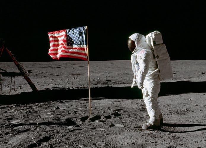 Astronauta ao lado de bandeira dos Estados Unidos na Lua