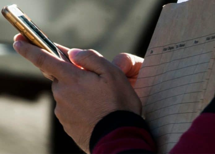 Pessoa usando celular enquanto carrega envelope