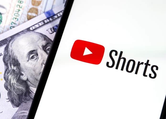 Celular com logomarca do YouTube Shorts na tela em cima de notas de dólar