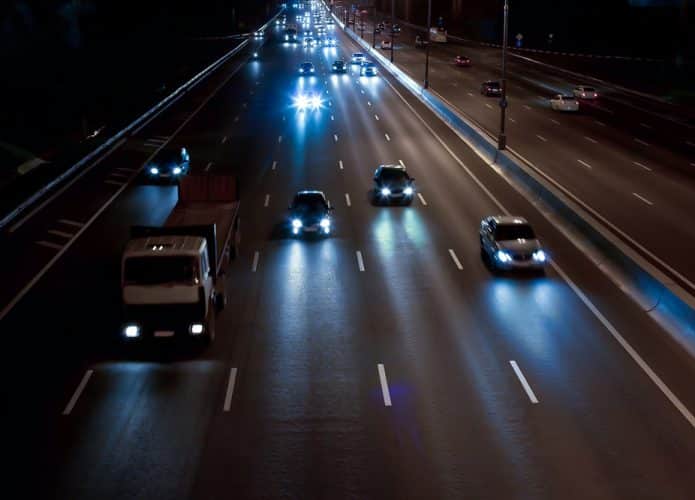 Carros trafegando na rodovia com farol ligado.