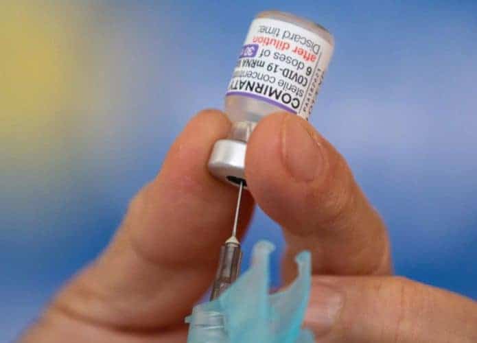 Enfermeiro carregando dose da vacina bivalente contra Covid numa agulha de injeção