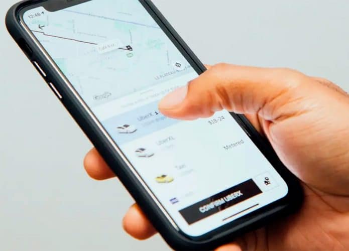 Pessoa segurando celular e prestes a confirmar viagem no Uber