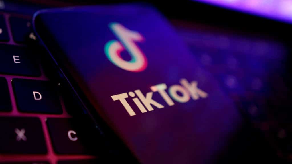 Celular com logomarca do TikTok aberta na tela em cima de teclado de notebook