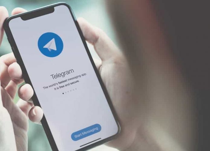 Pessoa segurando iPhone, no qual abre o Telegram pela primeira vez