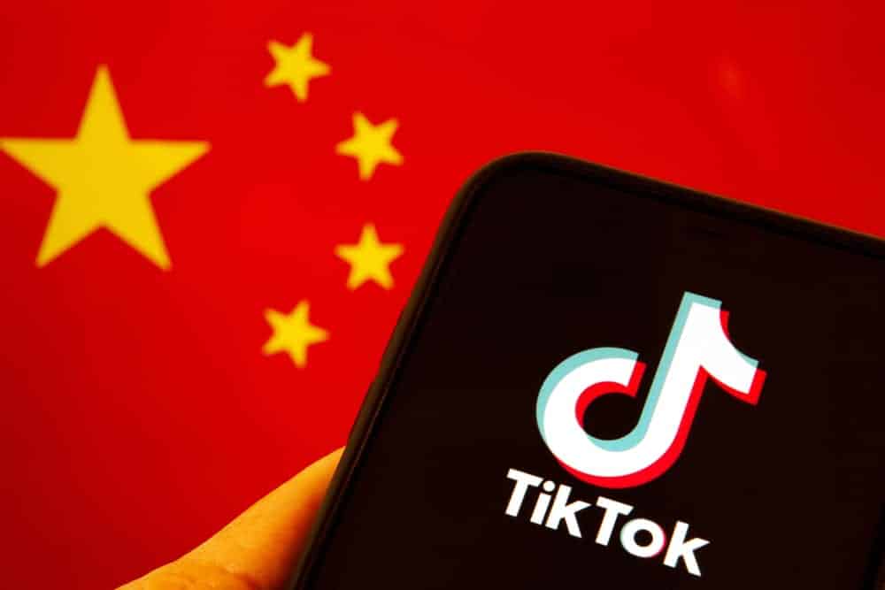 Celular com logo do TikTok na frente da bandeira da China.