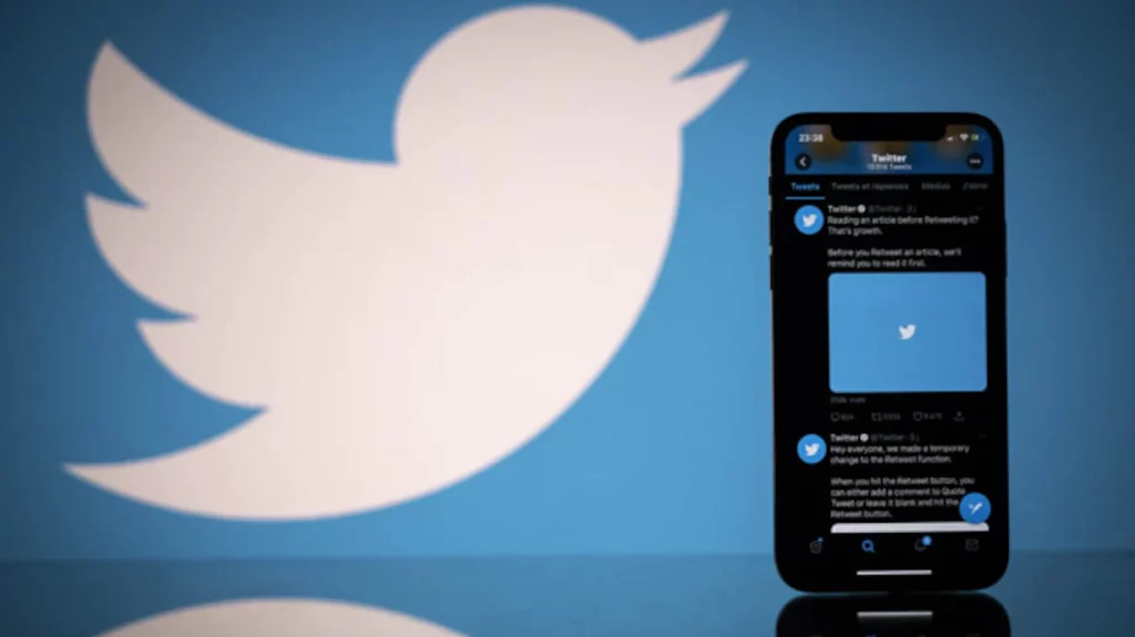 Perfil do Twitter aberto em iPhone com logomarca do Twitter ao fundo