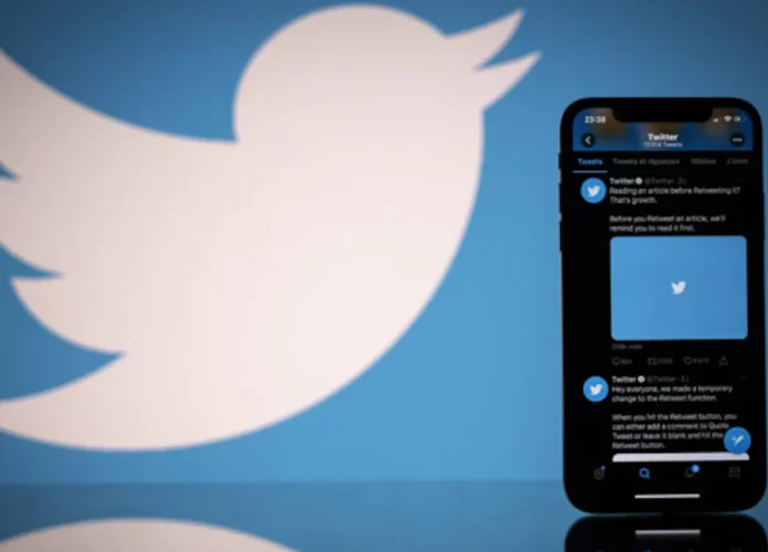Perfil do Twitter aberto em iPhone com logomarca do Twitter ao fundo
