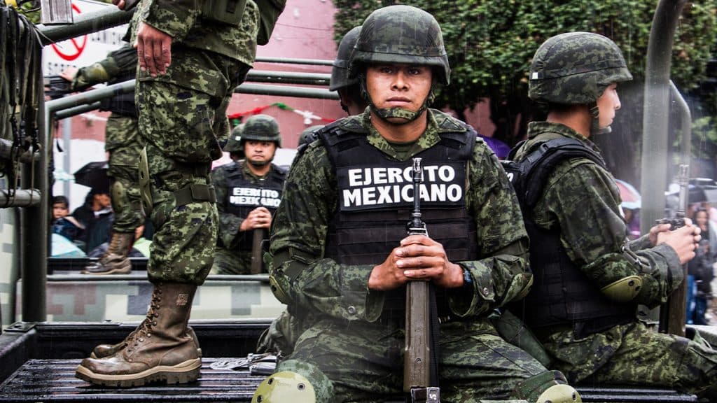 Militares do Exército do México sentados na caçamba de caminhão