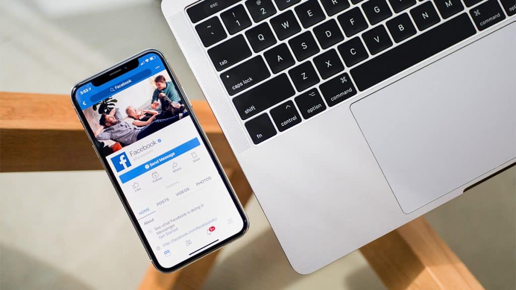 iPhone com página do Facebook no Facebook aberta ao lado de Macbook