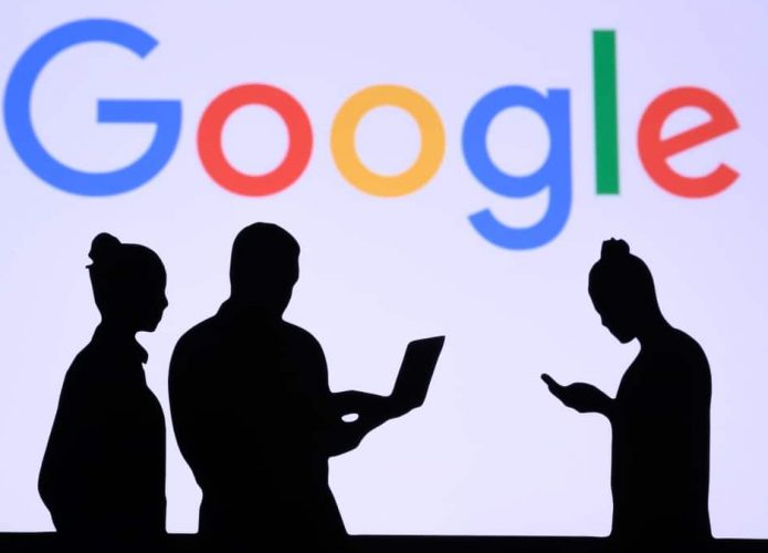 Silhuetas de um homem e duas mulheres na frente de um painel com a logomarca do Google