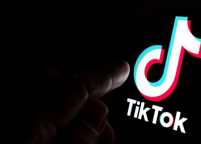 Pessoa com dedo sobre logomarca do TikTok na tela de um celular