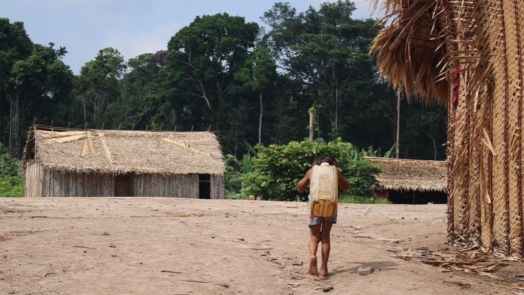 Criança Yanomami andando com galão de água nas costas