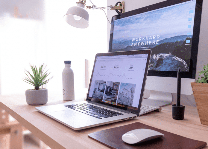Mesa de escritório home office com PCs iMac e Macbook