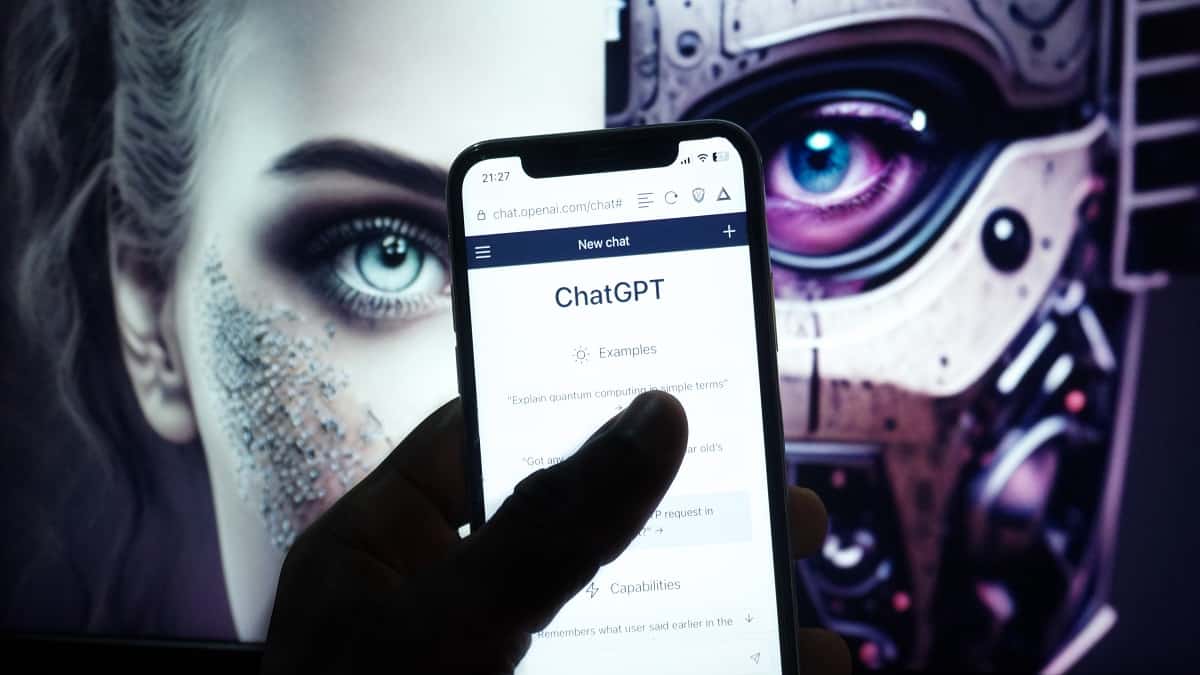 Pessoa com ChatGPT aberto num iPhone e imagem de inteligência artificial no fundo