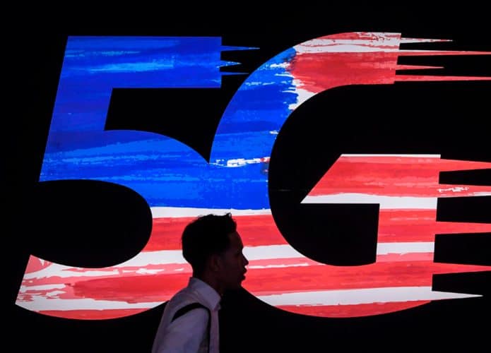 Pessoa passando por logomarca do 5G na Malásia