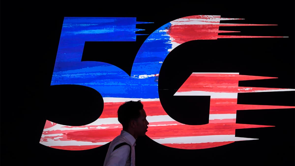 Pessoa passando por logomarca do 5G na Malásia