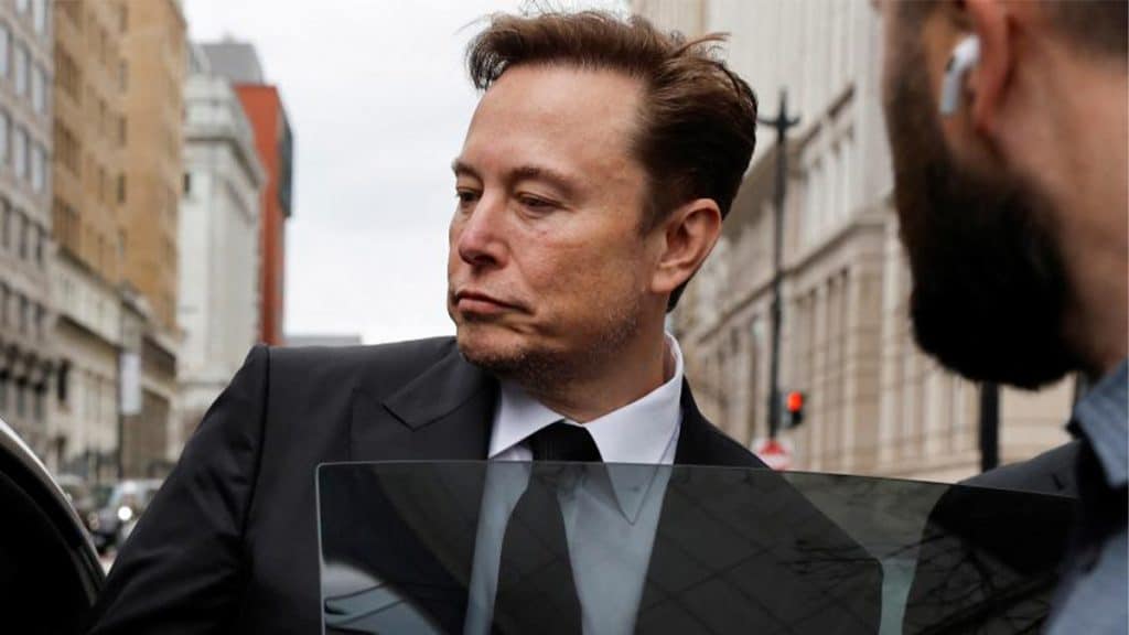 Elon Musk entrando em carro cercado por seguranças