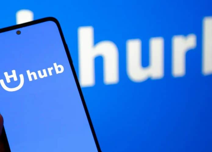 Celular com logomarca do Hurb aberta e, ao fundo, logomarca do Hurb aberta em tela de computador