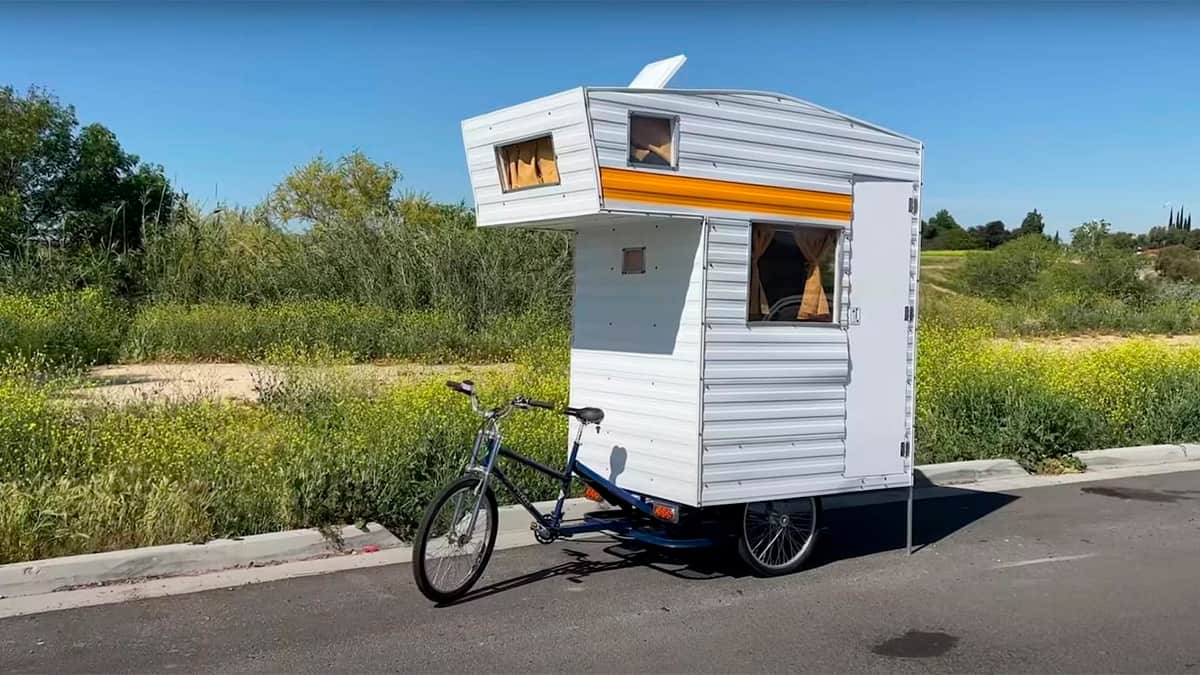 Bicicleta com trailer acoplado encostada na beira de uma rua