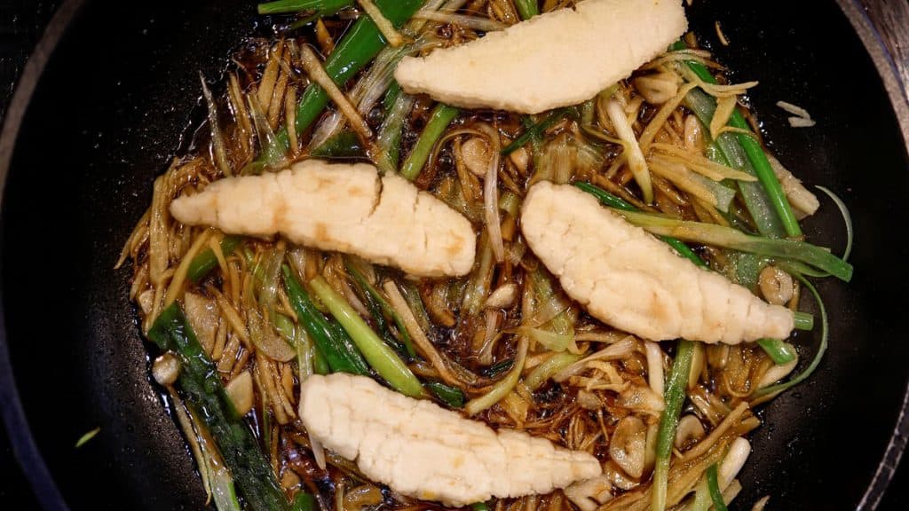 Tigela com espécie de yakissoba e filés de peixe impresso em cima