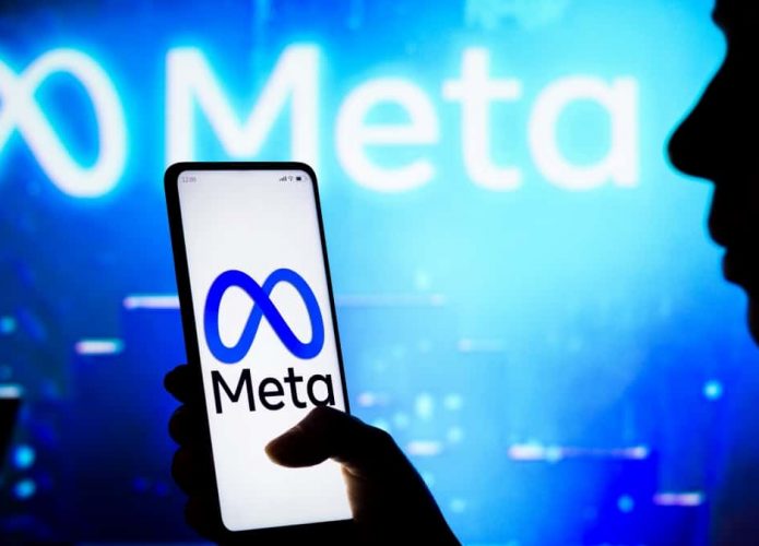 Silhueta de pessoa segurando celular com logomarca da Meta na tela, que também está no fundo