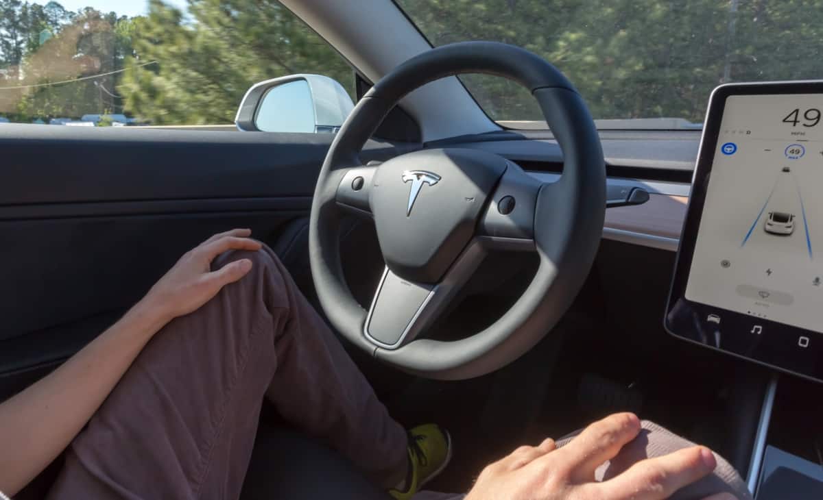 Motorista com mãos no joelho enquanto carro da Tesla está com piloto automático ativado