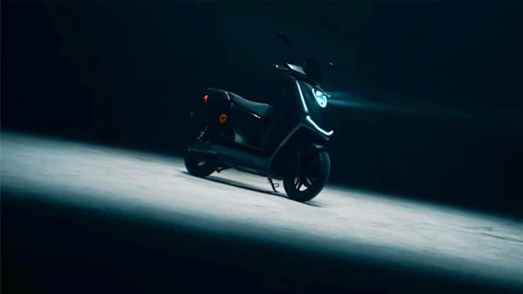 Scooter elétrica F200, da Yadea, com farol aceso e sob holofote num galpão escuro