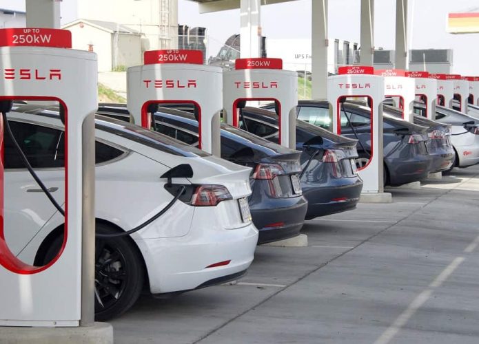 Fileira de carros elétricos conectados em totens de carregamento da Tesla