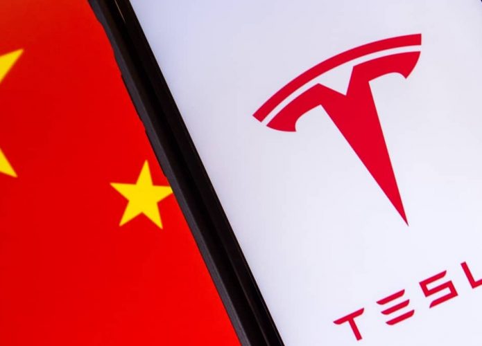 Celular com logomarca da Tesla na tela e bandeira da China ao fundo