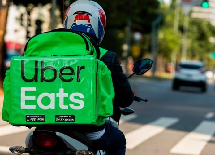 Homem dirige moto carregando mochila do Uber Eats