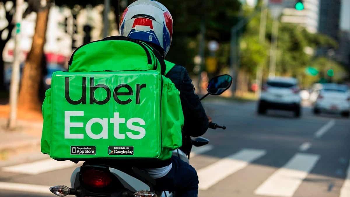 Homem dirige moto carregando mochila do Uber Eats