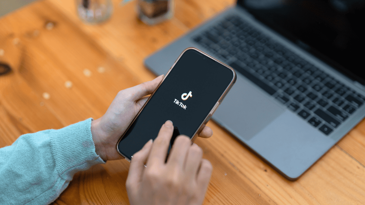Imagem mostrando uma pessoa manuseando o celular e abrindo o aplicativo do Tik Tok