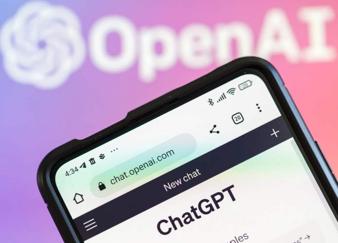 Celular com ChatGPT aberto num navegador com logomarca da OpenAI ao fundo