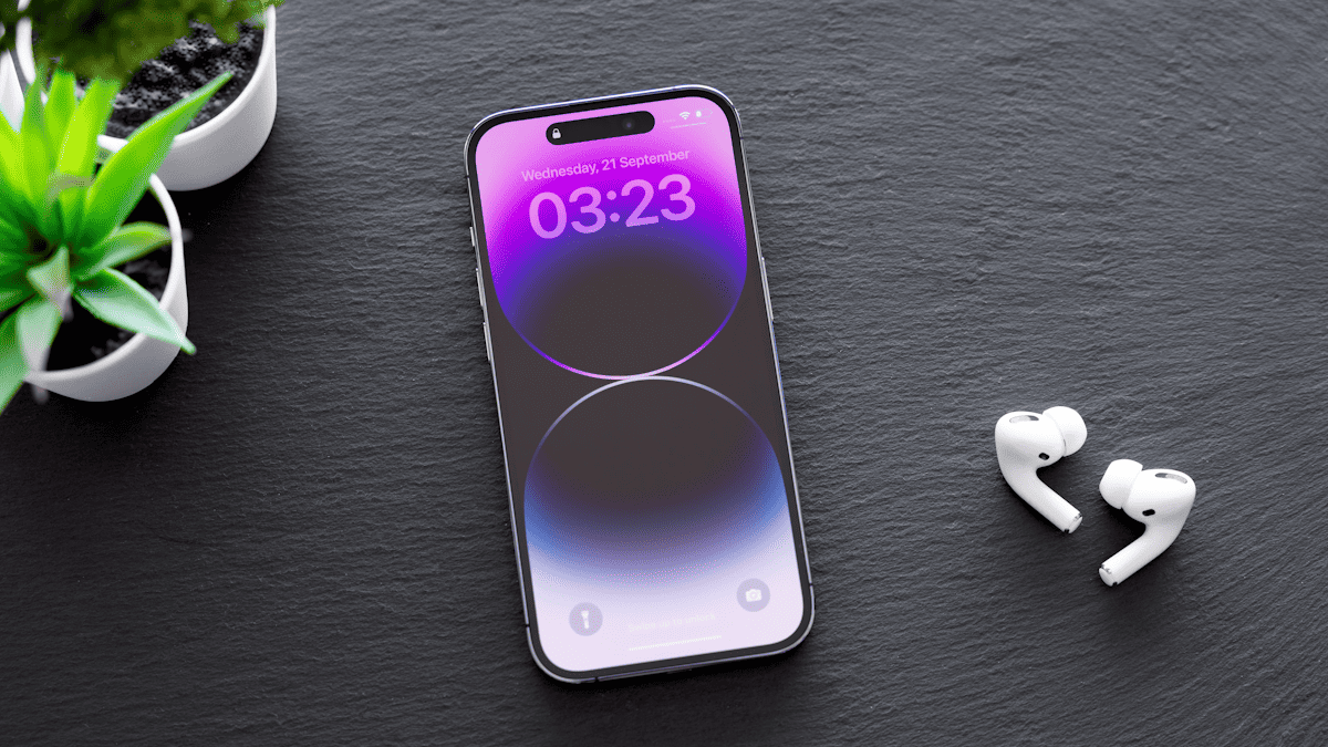 iPhone 14 Pro sobre uma mesa com par de AirPods do lado