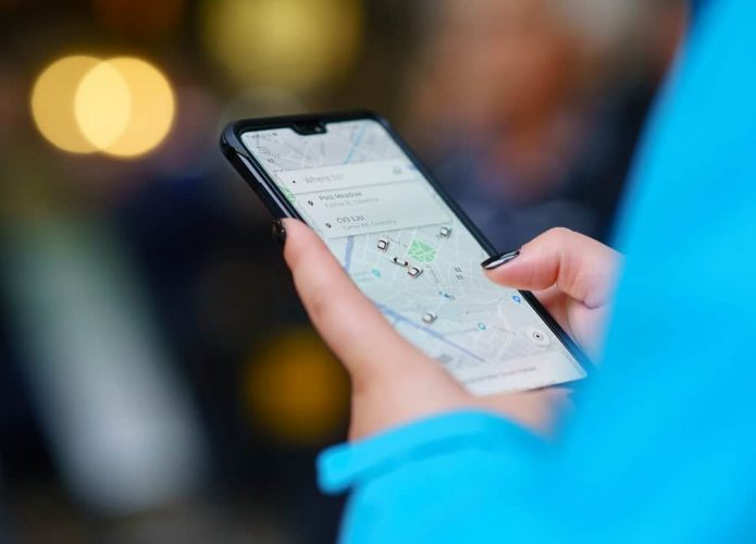 Pessoa com celular na mão pedindo por carona no Uber