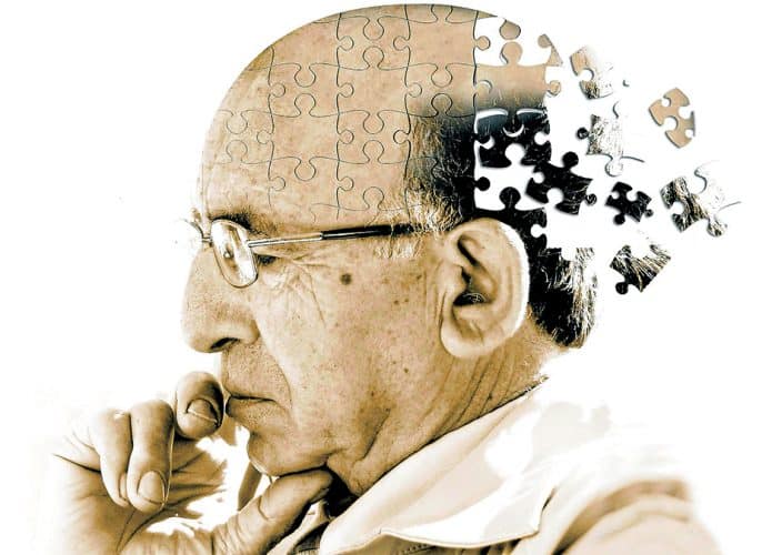 Ilustração de idoso se desfazendo em peças de quebra-cabeça para retratar conceito do Alzheimer